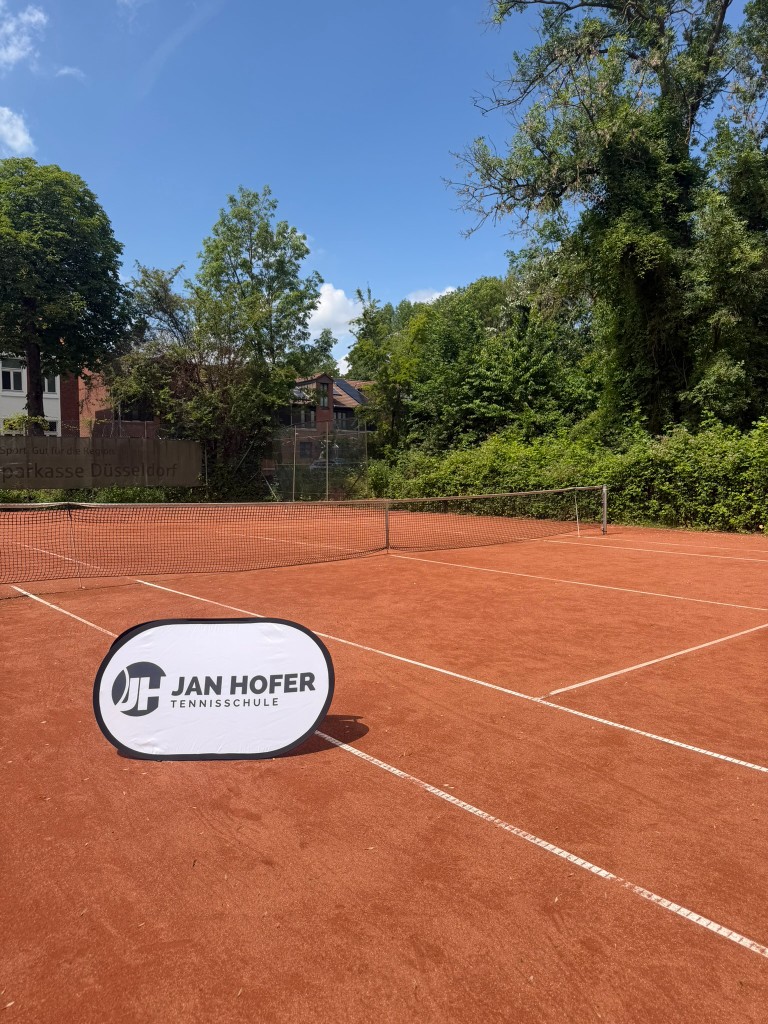 Tennisplatz mit JHT-Schild der Jan Hofer Tennisschule
