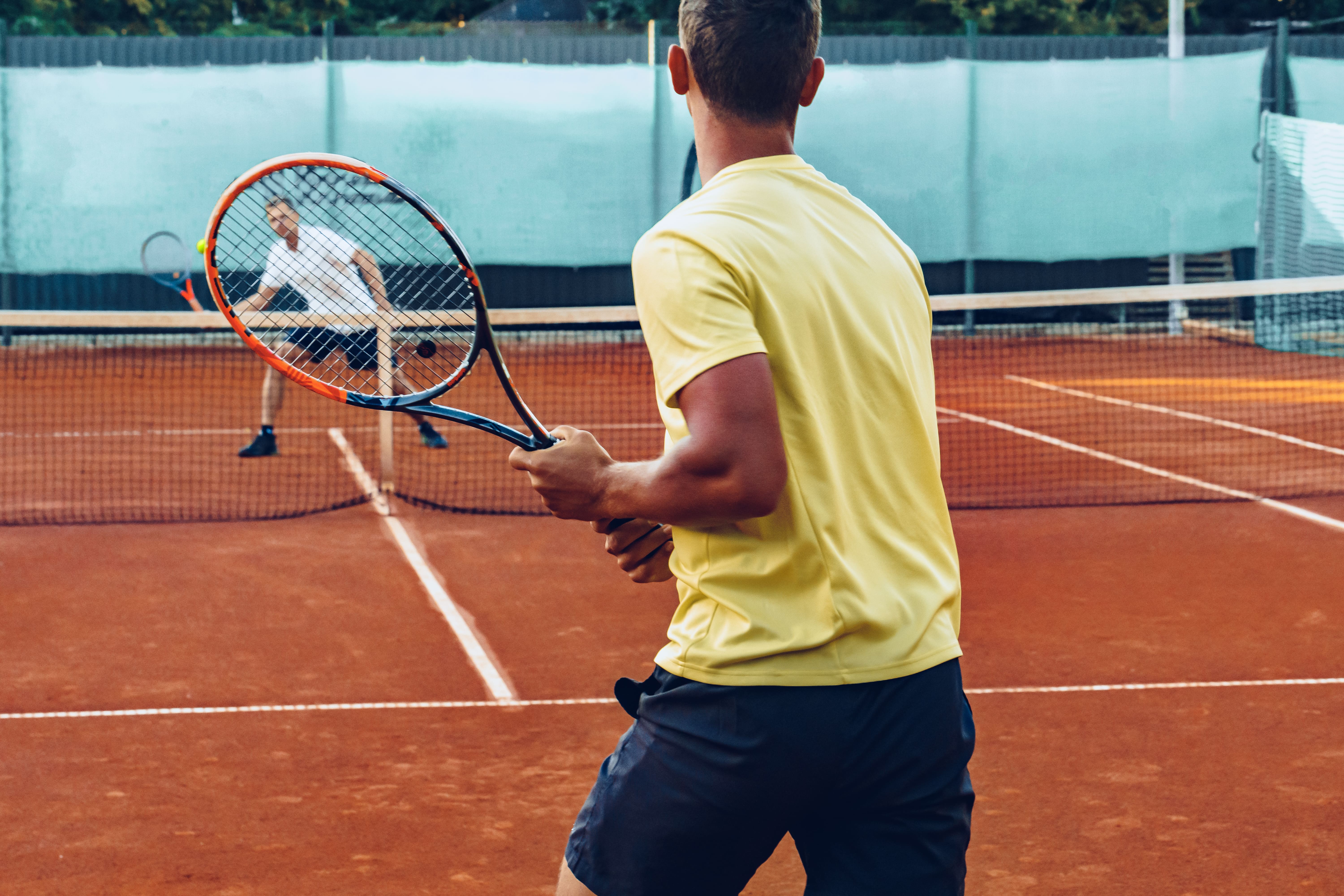 Zwei Erwachsene beim Tennis auf Sandplatz – Training und Matchnähe